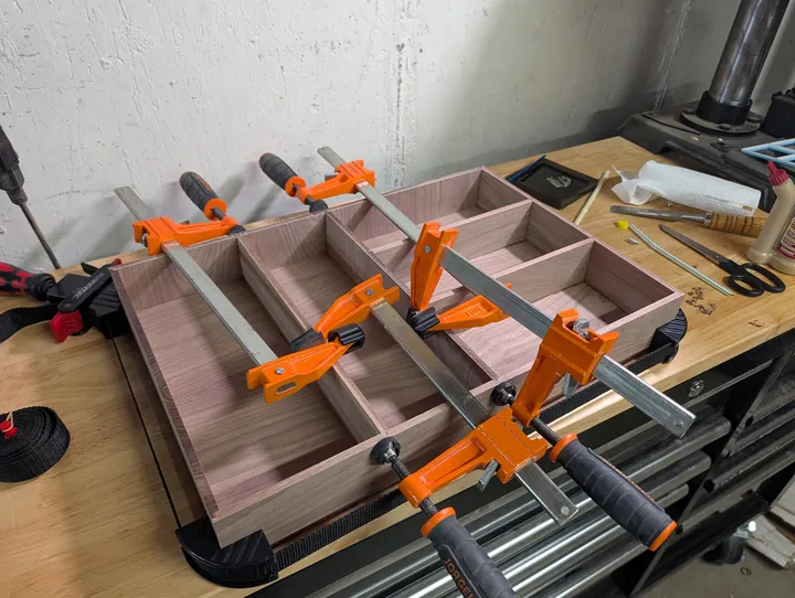 Bar clamps spanning the organizer and holding its walnut dividers in place