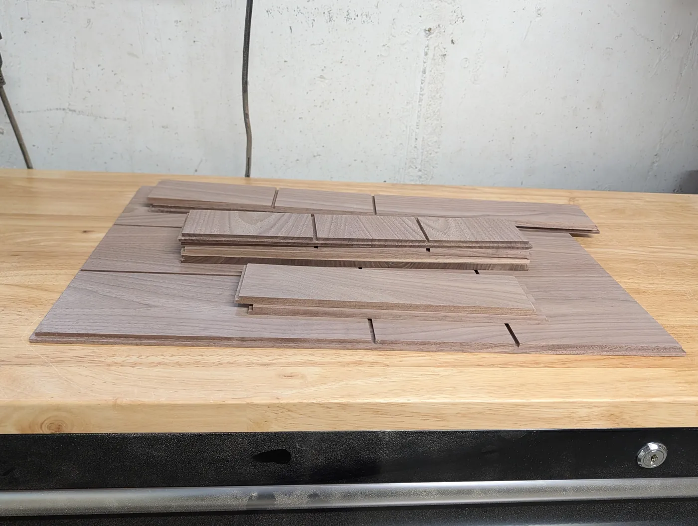 Walnut organizer panels and dividers stacked on a workbench before assembly