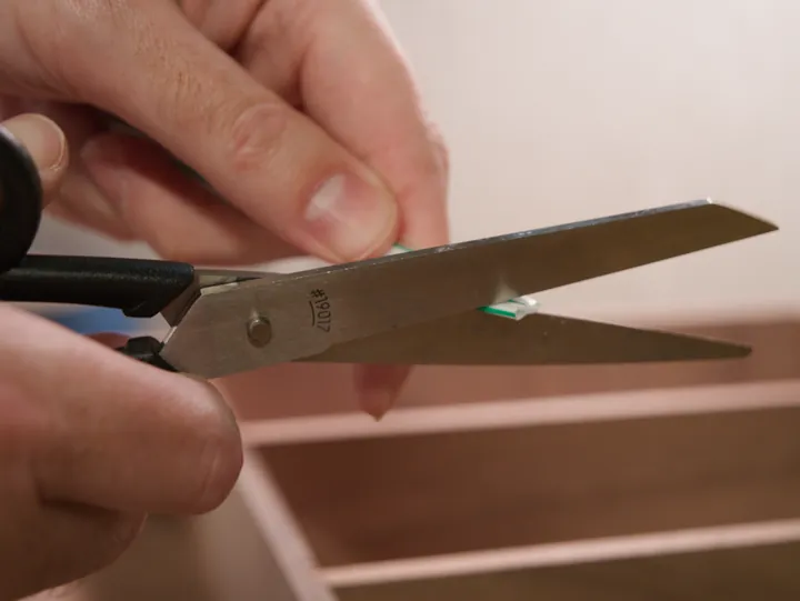 Cutting the end of a drinking straw at an angle for glue cleanup